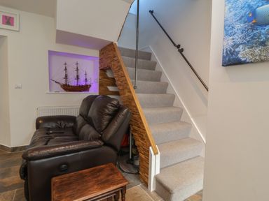 A hallway with a sofa and a staircase at Lenny's Place in Watchet