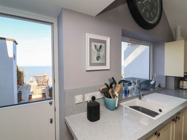 A kitchen with a view of the sea and utensils at Lenny's Place in Watchet