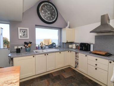 A kitchen with a clock and sink and large window at Lenny's Place in Watchet