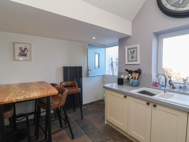 A kitchen with a sink and bar stools at Lenny's Place in Watchet
