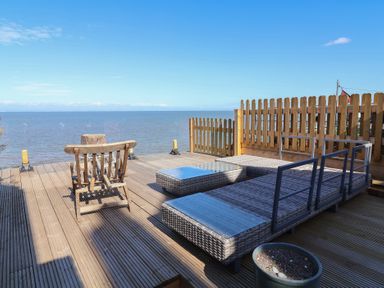 An outdoor area with sun loungers and a wooden chair at Lenny's Place in Watchet