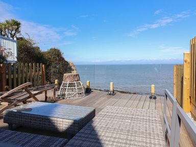 An outdoor deck with furniture overlooking the sea at Lenny's Place in Watchet