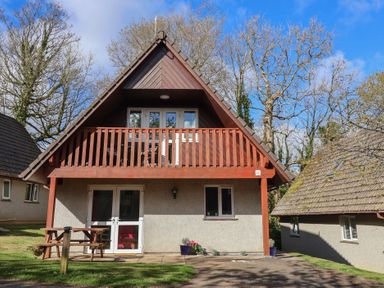 A house with a balcony and patio furniture at Mayfly Lodge St Tudy