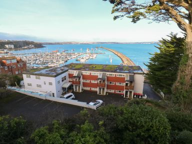 A view of a marina with buildings and cars at 20 Heath Court in Brixham