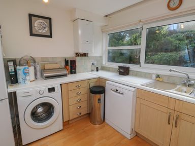 A kitchen with appliances including a washing machine and a dishwasher at 20 Heath Court Brixham