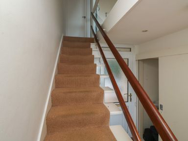 A staircase with a handrail and door at 20 Heath Court Brixham