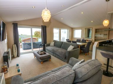 A living room with a sofa and dining area at The Hideaway in Pwllheli