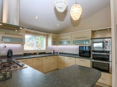 A kitchen with cabinets, sink, and appliances at The Hideaway in Pwllheli