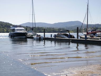 A dock with boats on water and mountains in the background at The Studio Windermere