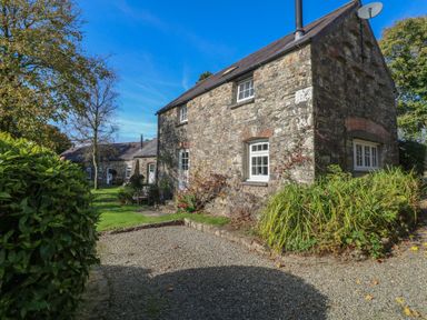 A stone house with trees and garden area at Carthouse Cottage in Clarbeston Road