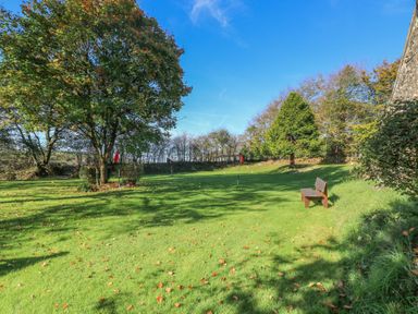 A garden with a bench and trees at Carthouse Cottage in Clarbeston Road