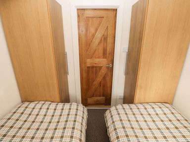 A bedroom with two beds and wooden wardrobes at Knap Cottage Clarbeston Road