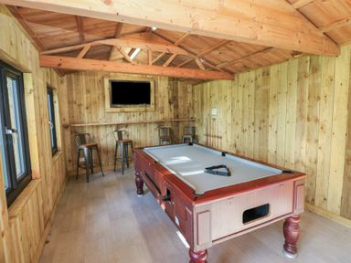 A room with a pool table and bar stools at Knap Cottage in Clarbeston Road