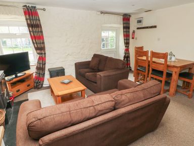 A living room with a sofa and dining table at Stable Cottage in Clarbeston Road