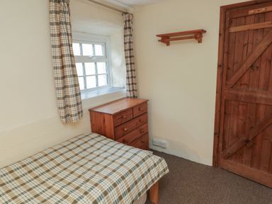 A bedroom with a bed, chest of drawers, and window at Stable Cottage in Clarbeston Road
