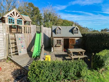 A garden with a playhouse, slide, and climbing wall at Stable Cottage in Clarbeston Road