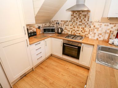 A kitchen with an oven, stove, microwave, and sink at Swallows Cottage in Clarbeston Road