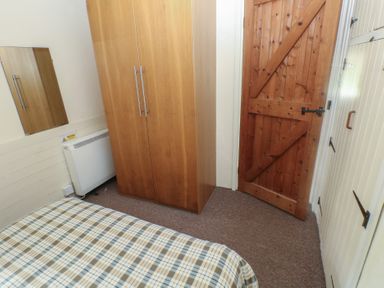 A bedroom with a wardrobe and a bed at Shippen Cottage in Clarbeston Road