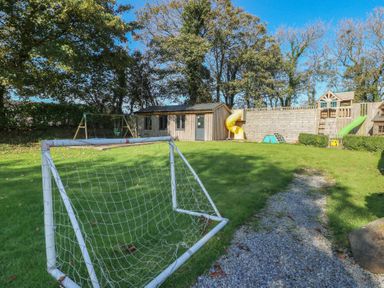 A garden with a soccer goal, swing set, and playhouse at Shippen Cottage in Clarbeston Road