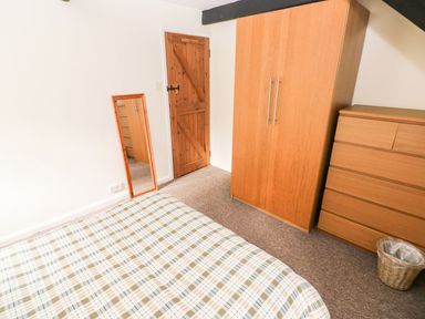 A bedroom with a bed, wardrobe, and mirror at Lake Cottage in Clarbeston Road