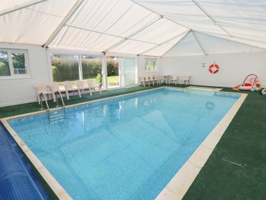 An indoor pool with chairs and a life ring at Lake Cottage in Clarbeston Road