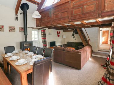 A living room with a fireplace and dining table at Granary Cottage in Clarbeston Road