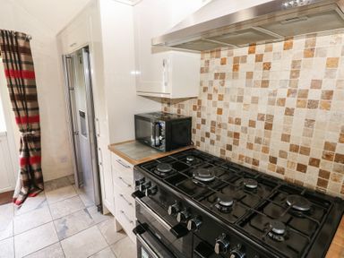 A kitchen with a stove, microwave, and refrigerator at Granary Cottage, Clarbeston Road