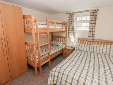 A bedroom with a bunk bed and a double bed at Granary Cottage in Clarbeston Road