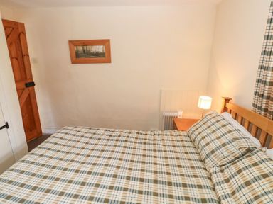 A bedroom with a bed and a lamp at Granary Cottage in Clarbeston Road