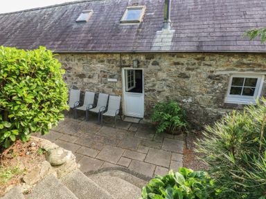 An outdoor patio area with chairs and plants at Granary Cottage in Clarbeston Road