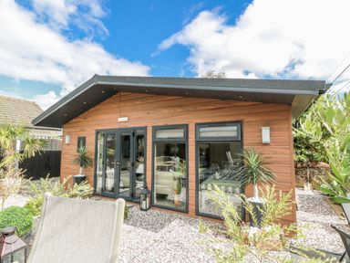 A cabin exterior with windows and plants in the garden at Cabin At The Brig Annan