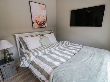 A bedroom with a bed and wall art at Cabin At The Brig in Annan