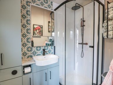 A bathroom with a shower, sink, mirror, and cabinet at Cabin At The Brig in Annan