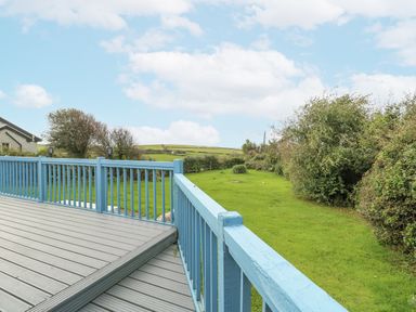 A deck overlooking a grassy area and bushes at Harbour Lights in Holyhead