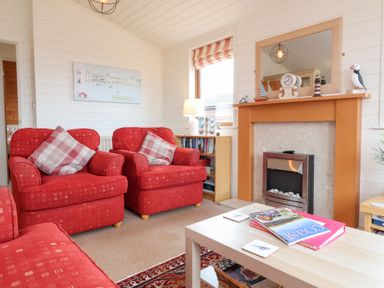 A living room with armchairs and a fireplace at Ocean Terrace 28 Ilfracombe