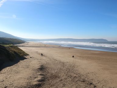 A beach with people walking near the water at Ocean Terrace 28 Ilfracombe
