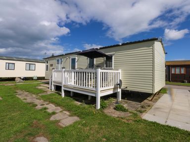 A static caravan with a deck and patio at Hideaway Lodge in Abergele