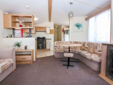 A living room with a sofa and dining table at Hideaway Lodge in Abergele