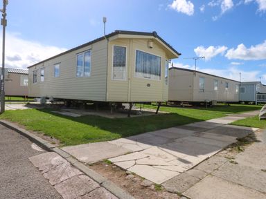 A static caravan on a path with grass at Hideaway Lodge in Abergele