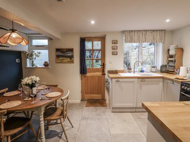 A kitchen with a dining table and sink at The Old Post Box in Halesworth