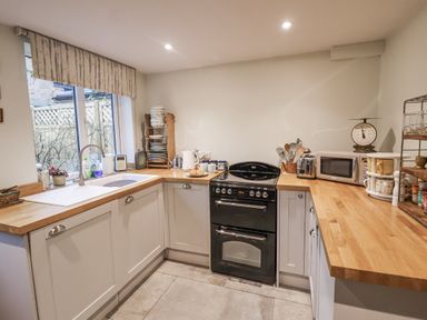A kitchen with a stove, microwave, and sink at The Old Post Box in Halesworth