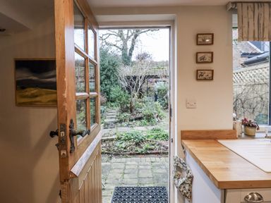 A kitchen with an open door leading to a garden at The Old Post Box in Halesworth