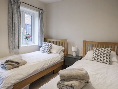 A bedroom with two beds and a window at The Old Post Box in Halesworth