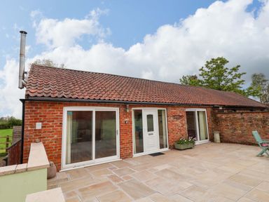 An exterior view of a brick building with a patio at The Owl Barn Cottage