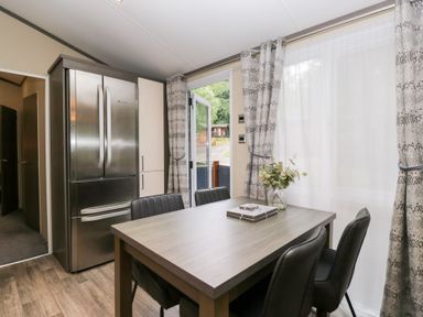 A kitchen with a dining table and refrigerator at Feather Hill Lodge in Windermere