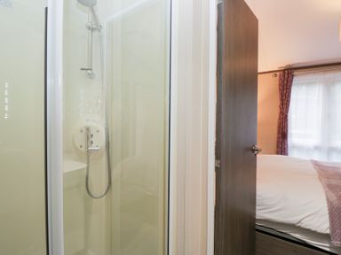 A shower in a bathroom with a door to a bedroom at Feather Hill Lodge in Windermere