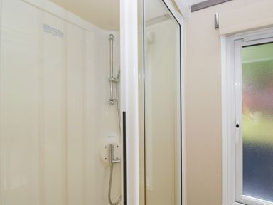 A shower with glass door and window at Feather Hill Lodge in Windermere