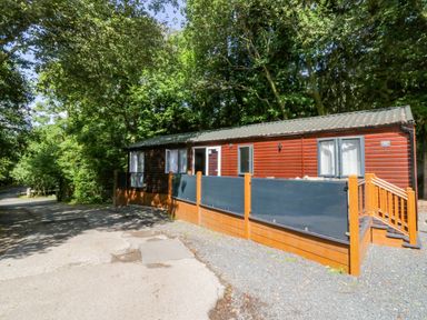 A cabin with a deck surrounded by trees at Feather Hill Lodge White Cross Bay, Skiptory Howe 38