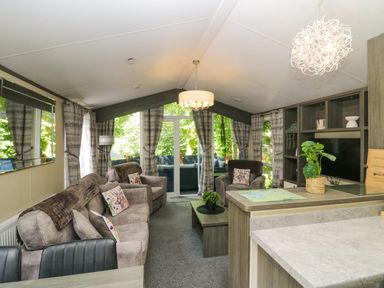 A living room with sofas, a coffee table, and a television stand at Feather Hill Lodge White Cross Bay near Troutbeck Bridge