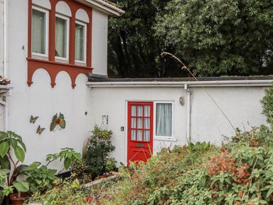 An outdoor area with a red door and decorative butterflies at Mayflower View in Dawlish
